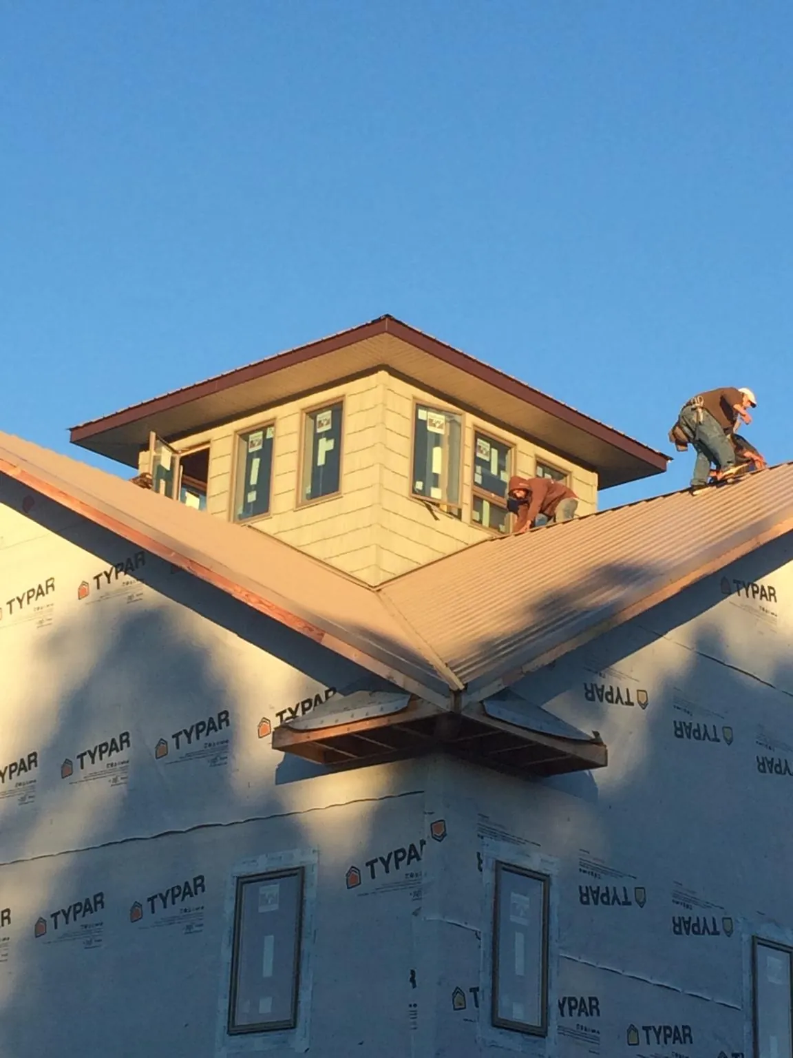 Roofers working around a rooftop cupola on a new metal roof at sunset — Roof Waterproofing in Hamilton by Roofing Brothers
